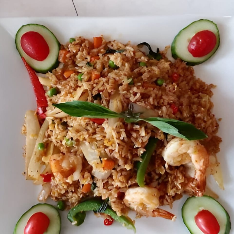 Thai fried rice with shrimp, vegetables, basil, and cucumber slices with cherry tomatoes.