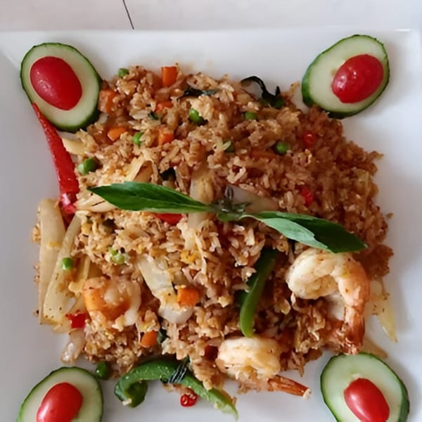 Thai fried rice with shrimp, vegetables, and basil, garnished with cucumber and cherry tomatoes.